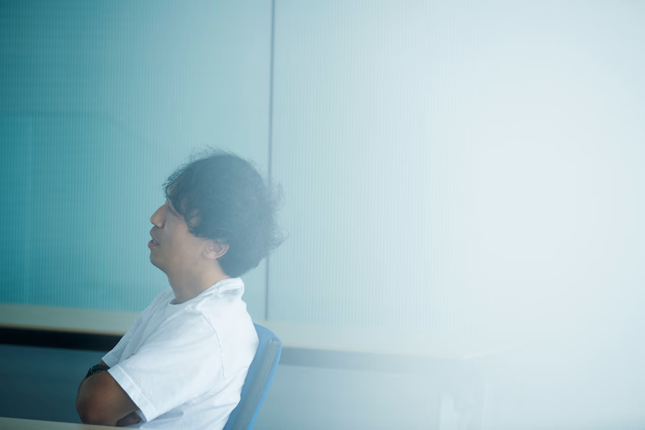 Kenta Jonai sitting in a chair at the research institute, looking to the side