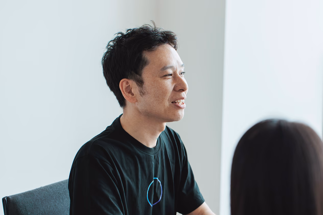 Yuji Kaneko sitting in an office chair, looking ahead and speaking