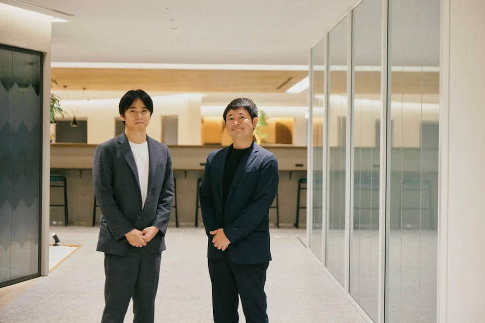 オフィスを背に並んで立つ坂井風太と浅井隆平